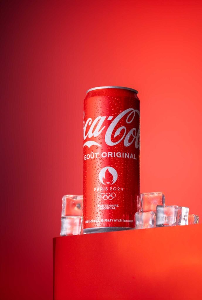 Une canette de Coca-Cola, entouré de glaçons, fraîcheur sur fond rouge