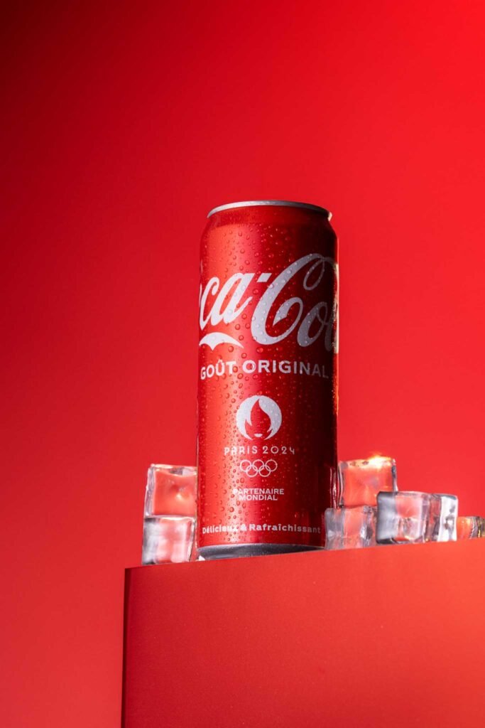 Une canette de Coca-Cola, entouré de glaçons, fraîcheur sur fond rouge
