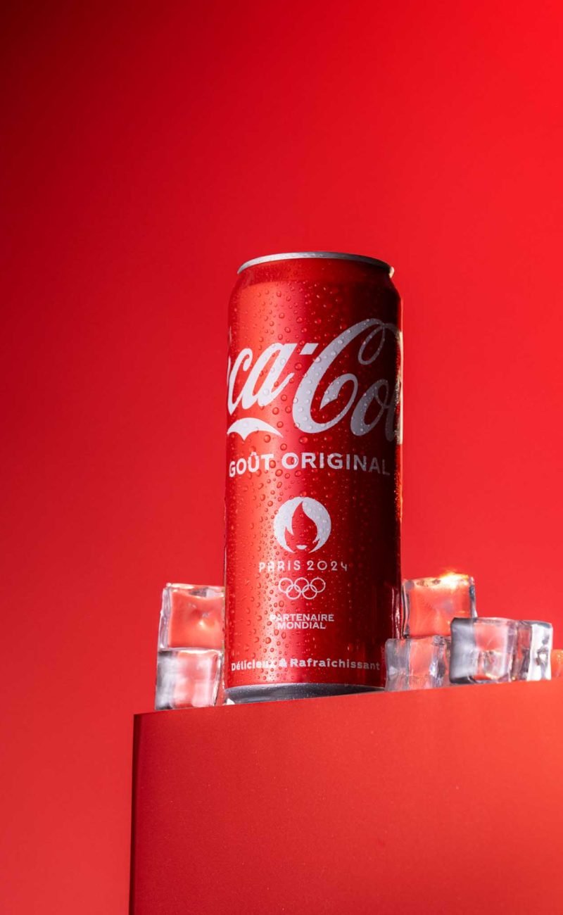 Une canette de Coca-Cola, entouré de glaçons, fraîcheur sur fond rouge